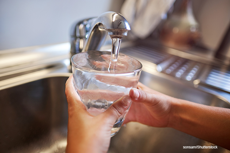 child filling a glass with tap water